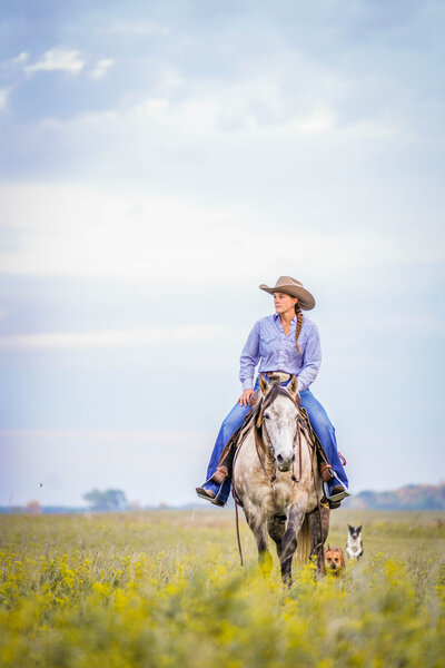Cowgirl Riding in the prairie with her cow dog western lifestyle session