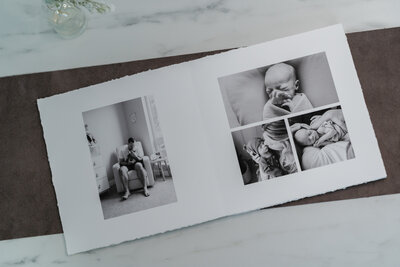 An open photo album with high-quality black and white images of a newborn, including close-ups of the baby being held by parents and resting peacefully.