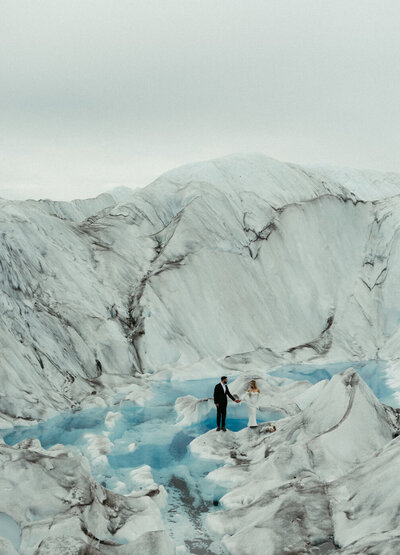 Couple standing on a glacier while holding hands.