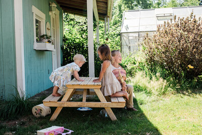 Three children sitting on picnic table back yard summer family photos
