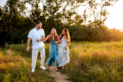 Stunning photo of a beautiful family of 3 walking with arms hooked and laughing while lookin at each other  in  Cliff Cave Park in Oakville, Missouri.