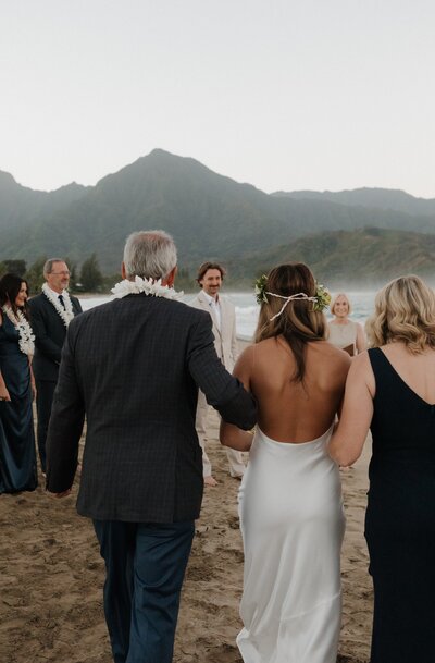 bride walking down aisle to groom on beach in kauai at Hanalei Bay