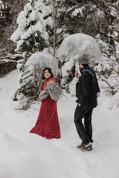 Bride and groom hike through snowy Rocky Mountain National Park during winter wedding.