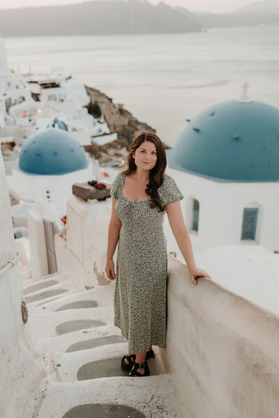 Female portrait on the white stone steps in front of the blue domes, Santorini Greece