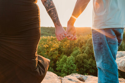 Engaged couple making a pinky promise while holding hands at Garden of the Gods in Southern Illinois during their engagement session, with golden hour light and scenic rocky overlook. displaying a beautiful engagement ring 