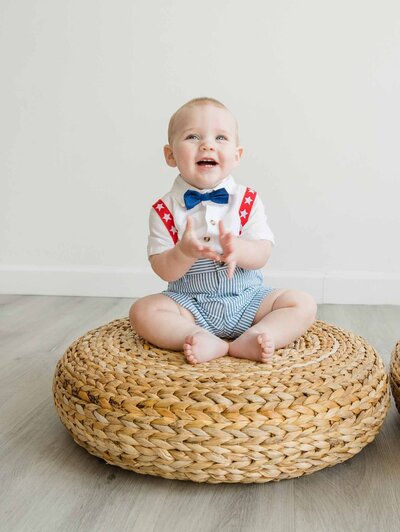 Baby boy during portrait session sitting on woven settee