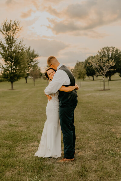bride and groom hugging in front of a beautiful sunset