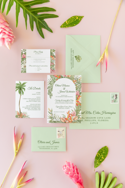 wedding invitation with tropical elements including palms and birds of paradise