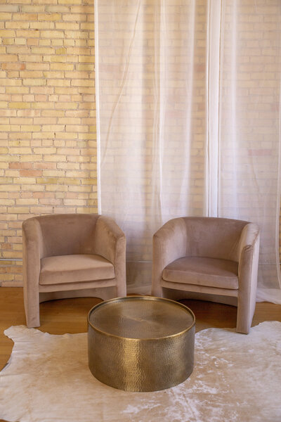 Two mauve velvet chairs with a round gold coffee table.