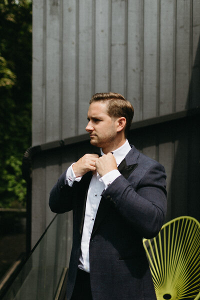 The groom adjusts his tie on the patio of the Drake Devonshire hotel in Prince Edward County, Ontario. Wellington wedding photographer, Jennifer van Son captured the scene.