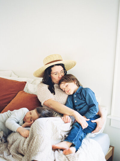 mom snuggling two sons in her home