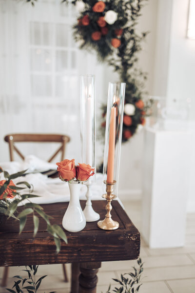orange roses and candles sitting on a wooden table