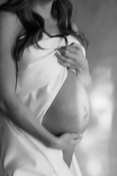 Fine art maternity session with a white sheet at downtown Milwaukee studio taken by Allexx B Photography