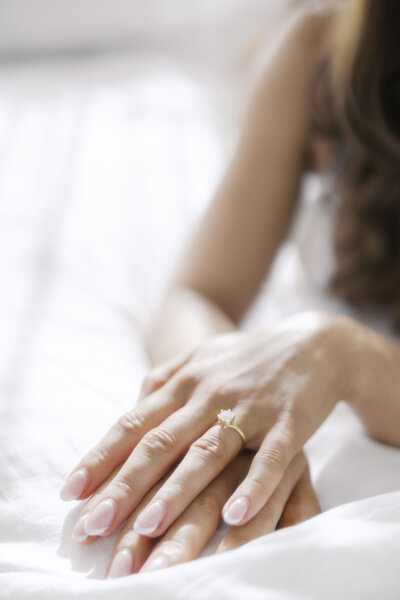 Young woman lying on bed for bridal boudoir photoshoot