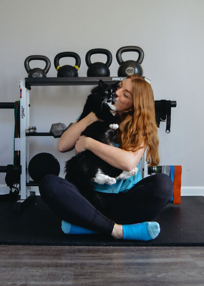Virtual Trainer sitting on floor holding a black and white cat