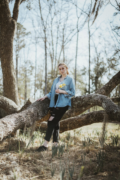 girl holding flowers by tree branches at hilton head portrait session