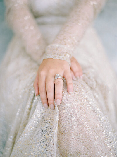 brides engagement ring showing off with sequin dress