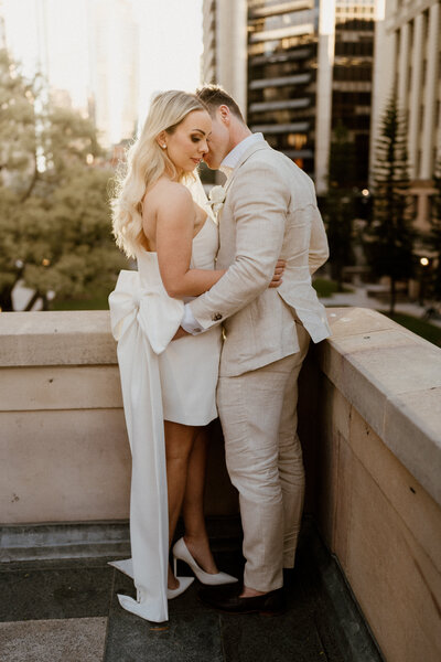 Bride and Groom cuddle as they bask in the sunset glow in the middle of Brisbane city - Wedding photographer in Brisbane, Brisbane luxury wedding photographer