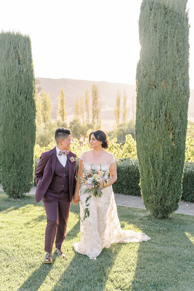 an lgbtq couple walks holding hands at their viansa winery wedding.