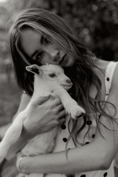 Black and white portrait of a young woman in a polka dot dress holding a baby goat, showcasing a gentle and emotional farm-inspired editorial session in Greenville, South Carolina. Dani Lacey Photographs.

Black and white portrait of a young woman in a polka dot dress holding a baby goat, showcasing a gentle and emotional farm-inspired editorial session in Greenville, South Carolina. Dani Lacey Photographs.