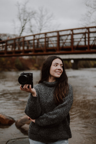 A professional photographer Golubski Photography  poses in front of a picturesque bridge in Cuyahoga Valley National Park, camera in hand. Surrounded by the park’s natural beauty, this shot captures the photographer's passion for both nature and photography, offering a glimpse into the artistic vision behind every session. Perfect for showcasing your Cleveland-based photography business and love for outdoor settings.