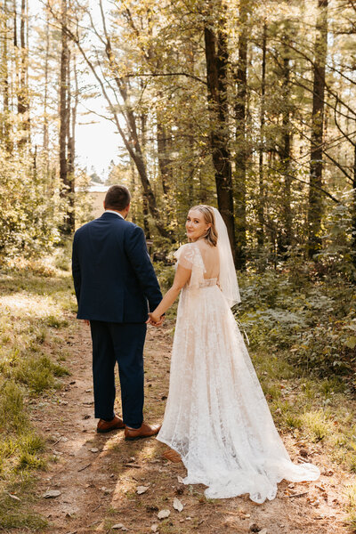bride and groom holding hands walking in forest