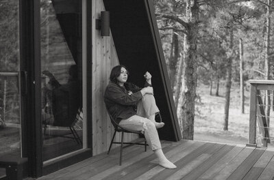 A portrait of Colorado elopement photographer, Rachel Kobernik on the porch of an Aframe cabin