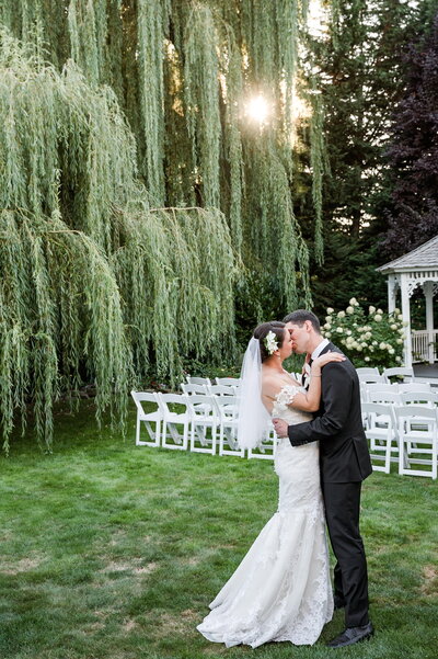 Bride and groom garden ceremony kissing by willow tree