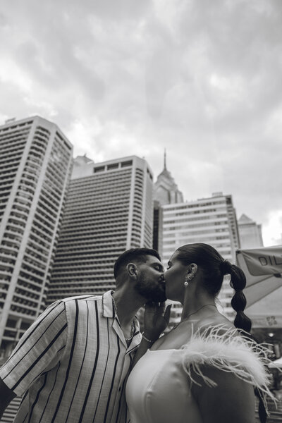 Couple sharing a kiss in downtown Philadelphia with skyline in the background