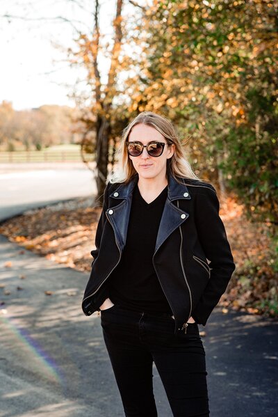 Blonde girl wearing sunglasses and leather jacket looking at camera