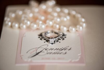 pocket--sized wedding invitation under pearl necklace
