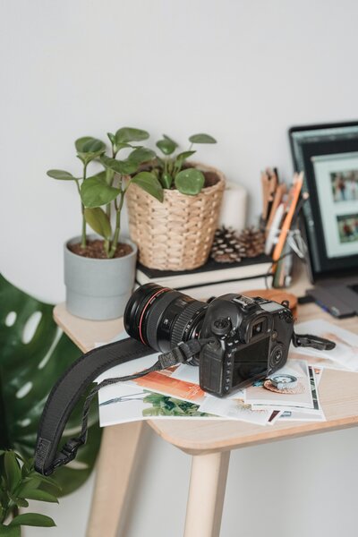 Showit web designer at desk with a camera, plants and laptop