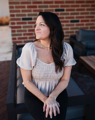 Alison Seponara in front of a brick wall smiling softly looking to the  side