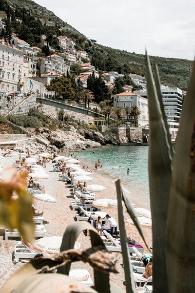 Perspective from above of a beach and sea. A cliff with houses in the background