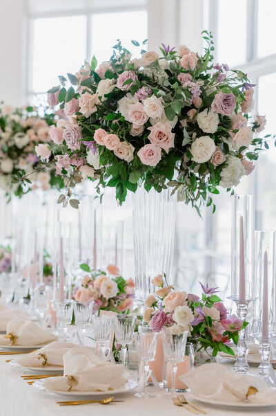 Beautiful wedding reception table with tall lush pink and white floral centerpieces
