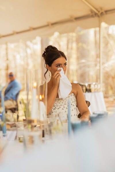 Bride wipes away tears listening to a toast at her wedding reception in Tallahassee, Florida