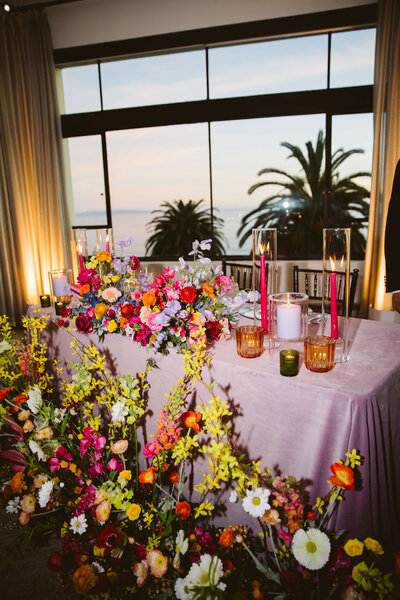 Three tier wedding cake on a round table covered in flowers at Current at Pier 59
