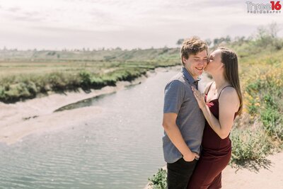 Bride to be whispers in her Groom's ear during photo shoot along the creek in the Upper Newport Bay Nature Preserve