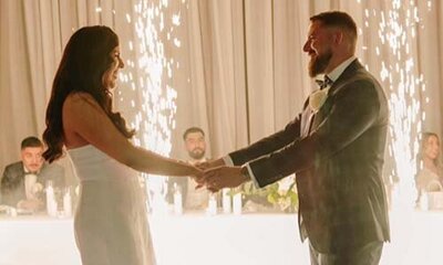 Bride and groom holding hands in front of sparkling indoor fireworks during their wedding reception
