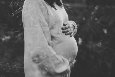 Vriend en vriendin die een kindje verwachten en een zwangerschapsshoot doen. De zwangere houdt haar buik vast waar de baby inzit en loopt hand in hand met haar man. Ze zijn in de natuur op de Veluwe bij Apeldoorn tijdens golden hour