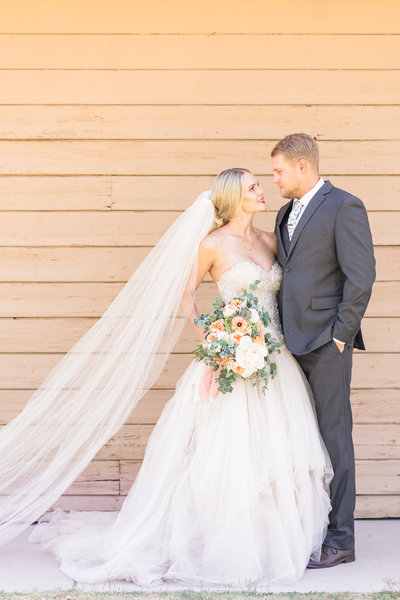 Bride and groom with pastel flowers and veil