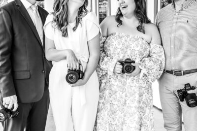 A black and white shot of Reg, Kala, and 2 other photographers from the neck down so you can't see anybody's face. Everyone is holding their camera.
