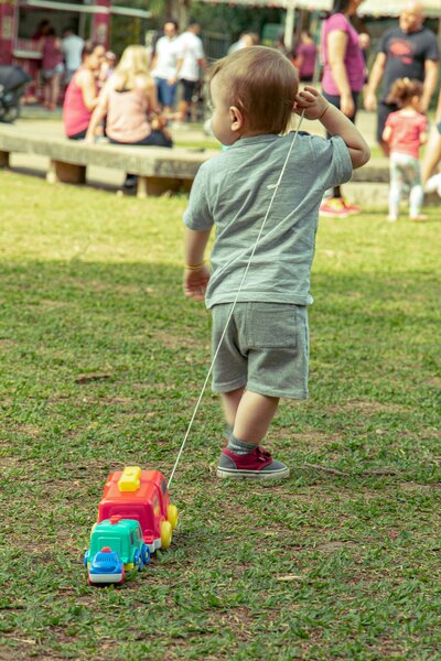 Little boy engaging in child development through play with a toy car in a forest setting at an early childhood education program in East Dallas, TX.
