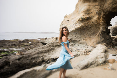Bride to be twirls her dress on the beach during an engagement photo session