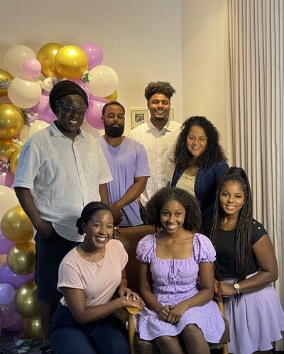 Juma Waganda and her family posing for a group photo in front of a balloon arch