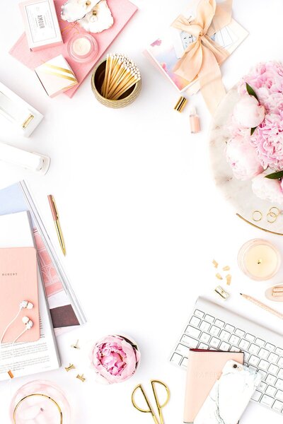 Overhead photo of a white desk covered in blush and champagne accents for stylized photo