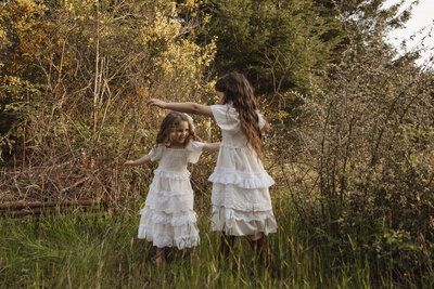 Two sisters hugging and sharing a sweet moment during an outdoor family photo session in Beverly Hills, capturing their close bond in a natural setting.