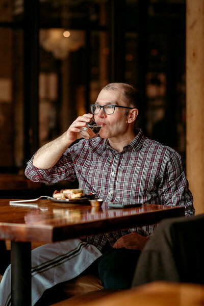 Candid lifestyle dating profile photo of Ryan laughing while enjoying a meal, showing real personality and confidence for his dating profile.
