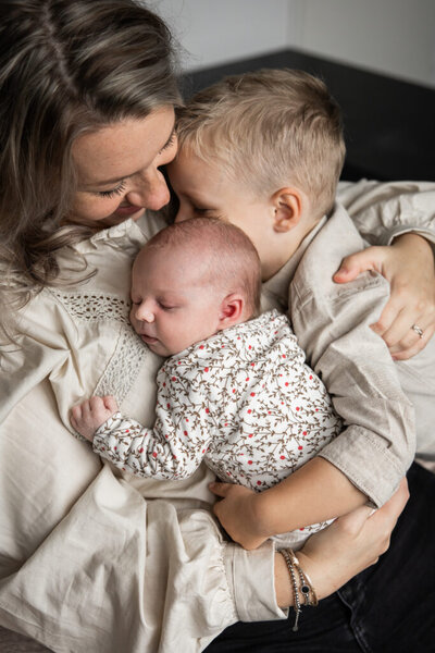 Moeder met baby en grote broer tijdens newbornshoot thuis