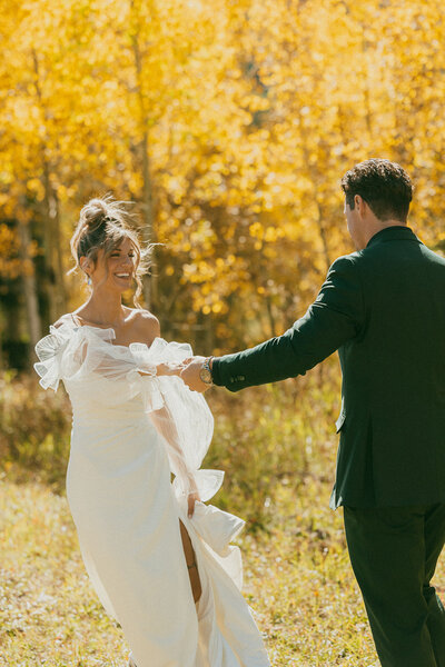 A couple exiting their wedding ceremony, cheering and dancing with their family and friends.